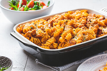 Baked pasta with chicken and cheese in oven dish, gray background. Italian cuisine concept.