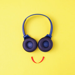 Headphones on a yellow background in the form of a happy face with a smile - Minimalistic...
