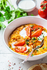 Vegan lentil soup with cilantro and tomato. Dal soup with tomatoes. Indian cuisine concept.