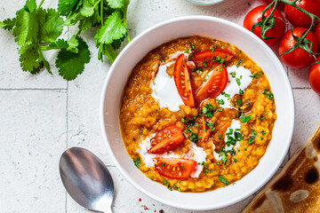 Vegan lentil soup with cilantro and tomato. Dal soup with tomatoes, top view. Indian cuisine concept.