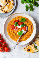 Vegan lentil soup with cilantro and tomato. Dal soup with tomatoes, top view. Indian cuisine concept.