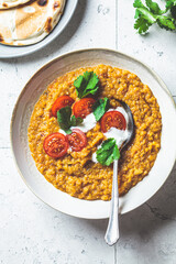 Vegan lentil soup with cilantro and tomato. Dal soup with tomatoes, top view. Indian cuisine concept.