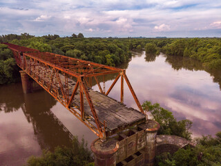 Beautiful view of the bridge over the water surrounded by thick forests during the sunset