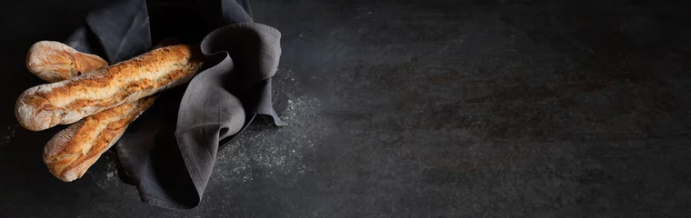 Rollo Brot Fresh crispy french baguette on black background. Atmosphäric food photography with space for text.  © gudrun