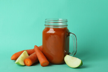 Glass jar of juice and ingredients on mint background