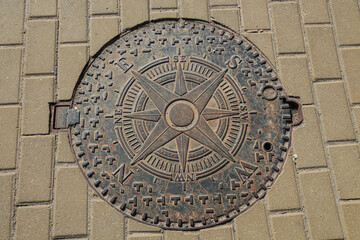 manhole with the image of the wind rose, compass, cardinal points.