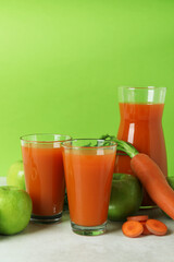 Glasses and pitcher with juice and ingredients against green background
