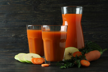Glasses and pitcher with juice and ingredients on wooden background