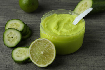 Jar with cosmetics, cucumber and lime on gray textured background