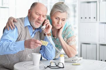 ill Senior couple  at home calling doctor
