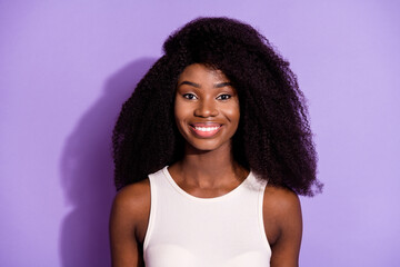 Portrait of attractive cheerful wavy-haired girl wearing white singlet isolated over bright violet purple color background