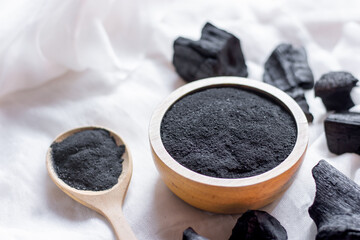 The black charcoal powder in the wooden cup was placed on a white cloth.