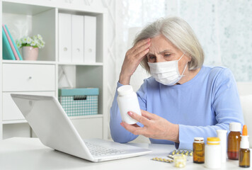 ill beautiful senior woman  with facial mask holding pills