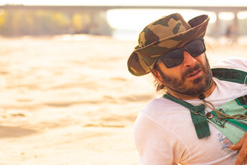 Hippy man with hat beard and glasses at the beach outdoors