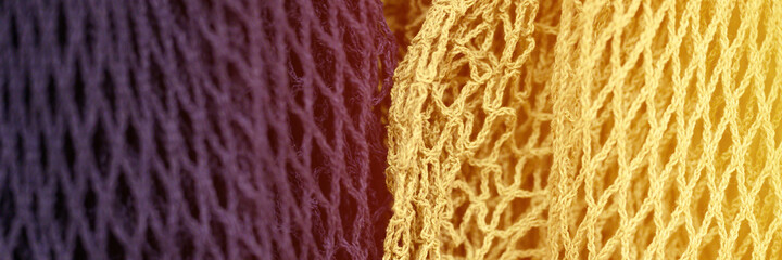 reusable shopping mesh bags purple and yellow colors close up. banner. flare
