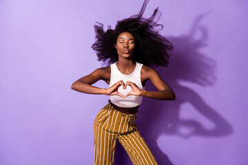 Portrait of charming dark skin lady closed eyes kiss lips fingers make heart figure isolated on purple color background