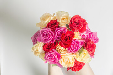 The woman's hands are holding a beautiful bouquet of fresh multicolored roses