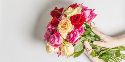 The woman's hands are holding a beautiful bouquet of fresh multicolored roses