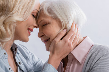 Positive woman with closed eyes hugging elderly mother