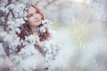 young girl spring portrait in a blooming garden, springtime happiness, rain weather in the park in...