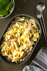 Fettuccini pasta with mushrooms and chicken breast and basil in a creamy sauce, top view