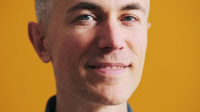 A close-up shot of the face of a smiling mature man in the studio
