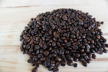 Coffee seeds pile isolated on wooden background closeup.
