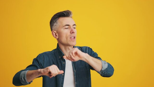 A mature man actively dancing with his hands in the studio