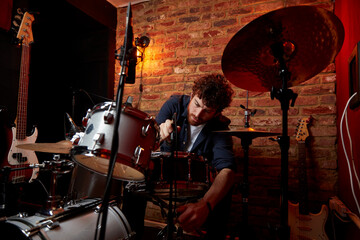 Man adjusting drum set in music studio