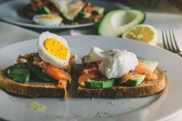 Healthy avocado toast with rye bread, salmon,seeds and egg on a plate