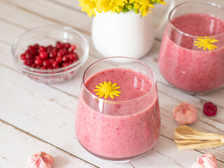 Pink cranberry smoothie on wooden table. Creamy and healthy vegan drink for morning breakfast. Weight loss diet concept.