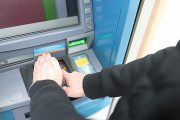Naklejka na ściany i meble Man entering pin code at ATM and covering it with his hand closeup