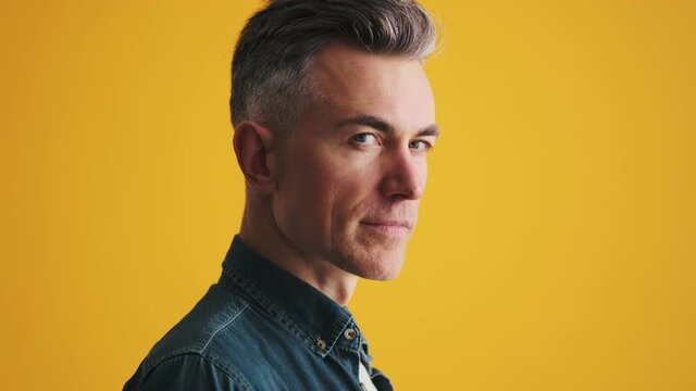 The side-view of a mature man turning to the camera and raising eyebrow in the studio