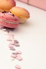 multicolored dessert macarons on a white background decorated with delicate candy hearts