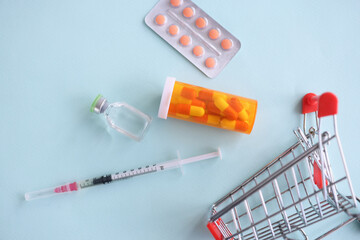 Many medicines and syringe lying near toy metal basket closeup