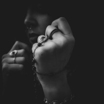 mujer sin rostro moderna rezando con mantilla anillos y un rosario