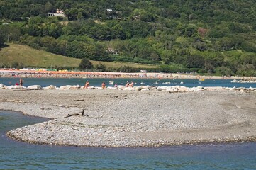 People are sunbathing on a pebble beach in the Pesaro bay (Marche, Italy, Europe)