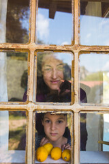 Obraz premium A boy with his mother curiously peeks out the window of a wooden house.