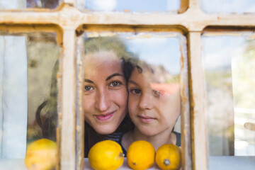 Obraz premium A boy with his mother curiously peeks out the window of a wooden house.