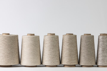 bobbins of natural fiber standing in a row, coarse linen isolated on white background