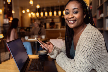 Fototapeta premium Portrait of young woman working on using laptop at coffee shop.
