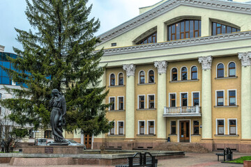 Poltava, Ukraine - April 14, 2021: Ancient bronze statue of the literary heroine Marusya Churai in front of the facade of the Nikolai Gogol Academic Theater of Poltava Ukraine. High art and urban view