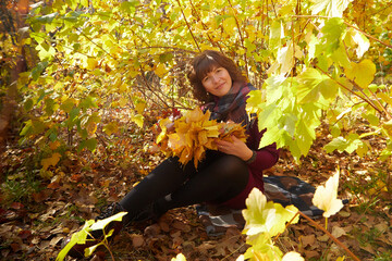 Portrait of mature woman in autumn park and trees with yellow leaves background