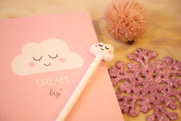 Pink notebook and wood table. Pink cell phone and artificial snowflake
