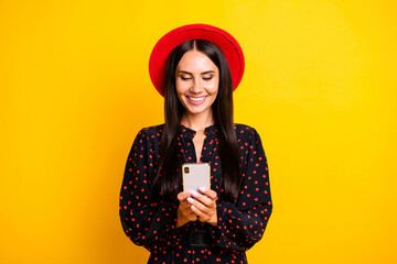 Photo of adorable sweet young woman wear dotted outfit headwear typing modern device isolated yellow color background
