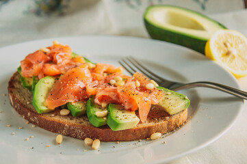 Healthy avocado toast with rye bread, sliced avocado,salmon,seeds, salt and pepper. Vegetarian food. Clean eating.