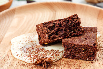 Traditional dessert. Chocolate brownie on a wooden plate on a light concrete background. Space for text. 