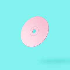 Vintage pink compact disc on bright blue background. Minimal pastel composition.