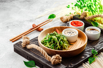 Pan-Asian food. Vegetable salad with chuka and cucumber on wooden plate on concrete background. Close-up. 