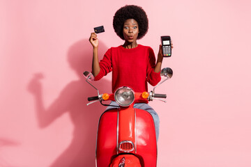 Photo of impressed attractive dark skin lady hold debit card pos terminal sit on bike isolated on pink color background